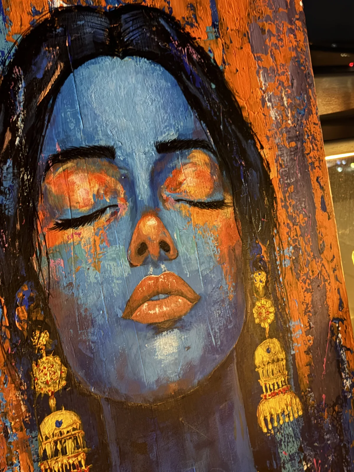 Abstract portrait in blue on rust and orange with gold jhumka earrings